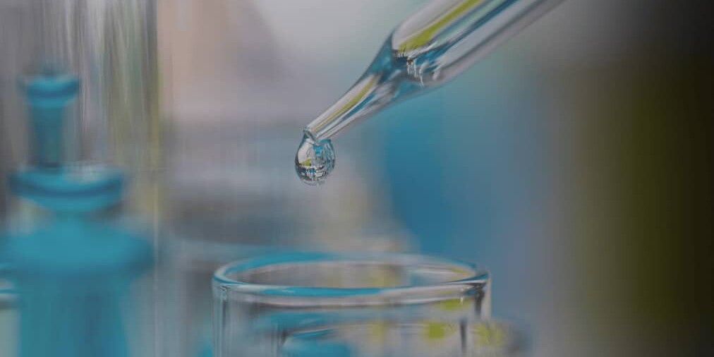 dropper dropping liquid into a glass beaker