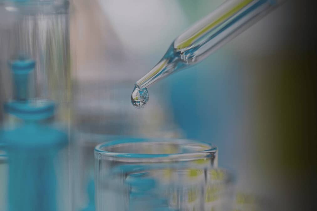 dropper dropping liquid into a glass beaker